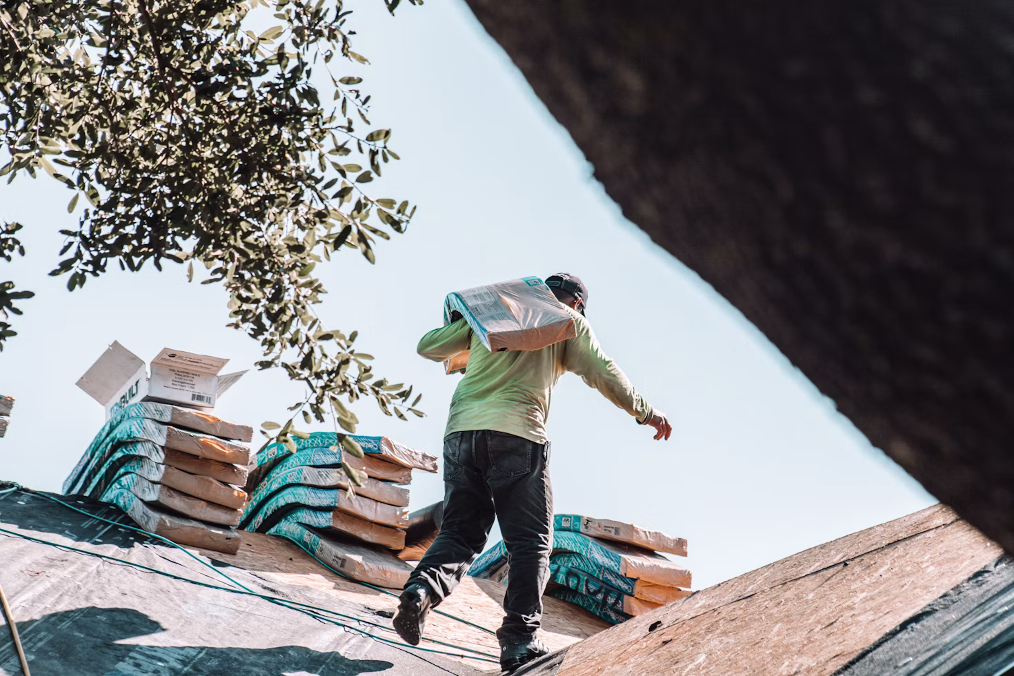 Roofer carrying shingles across a roof